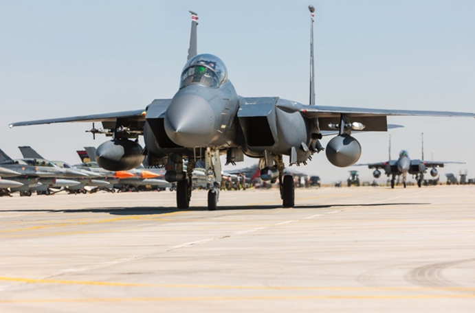 Photo of a military jet in an airfield, with other jets in the background